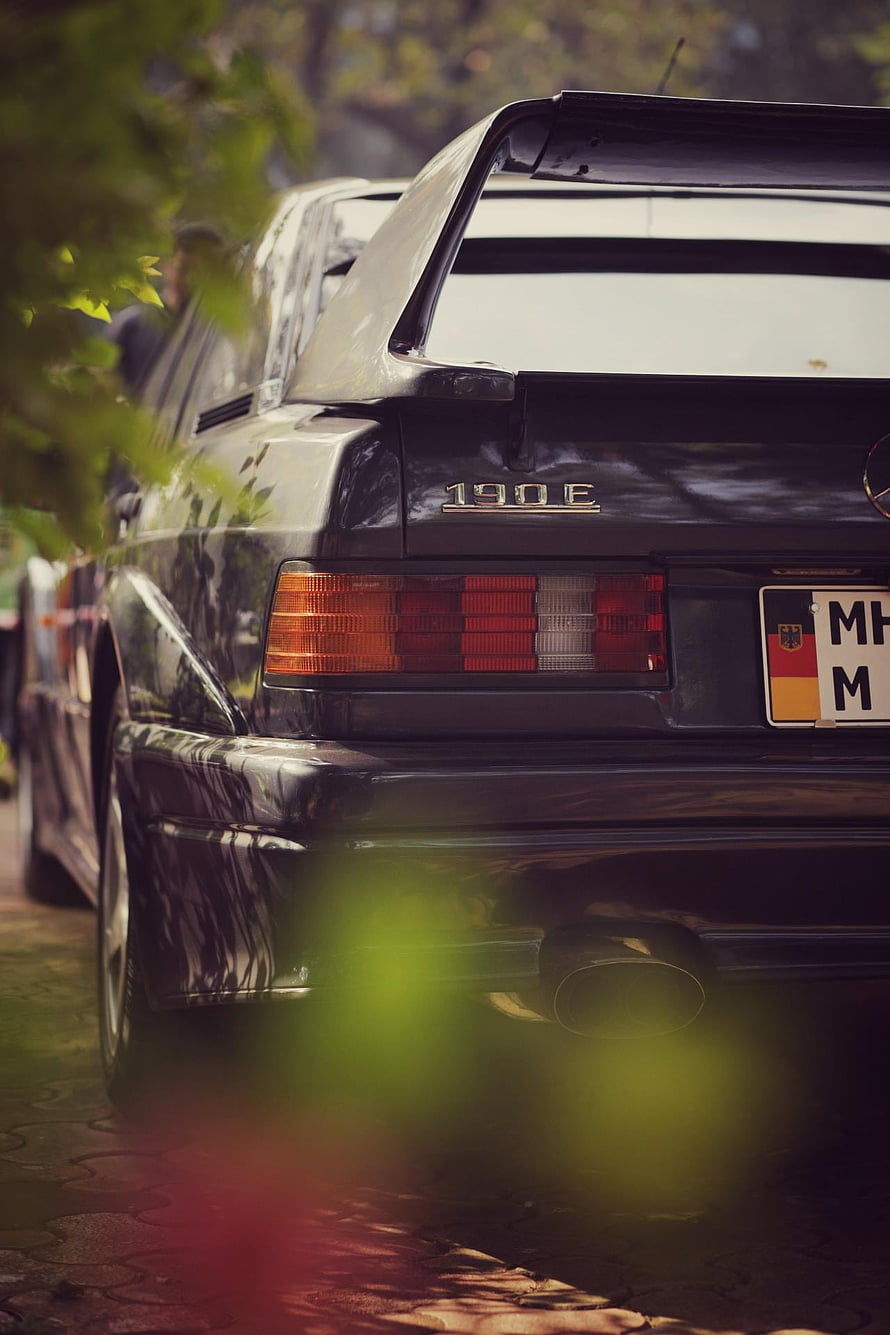 Rear View of a Classic Black Mercedes 190E with Prominent Spoiler and Taillights HD phone wallpaper