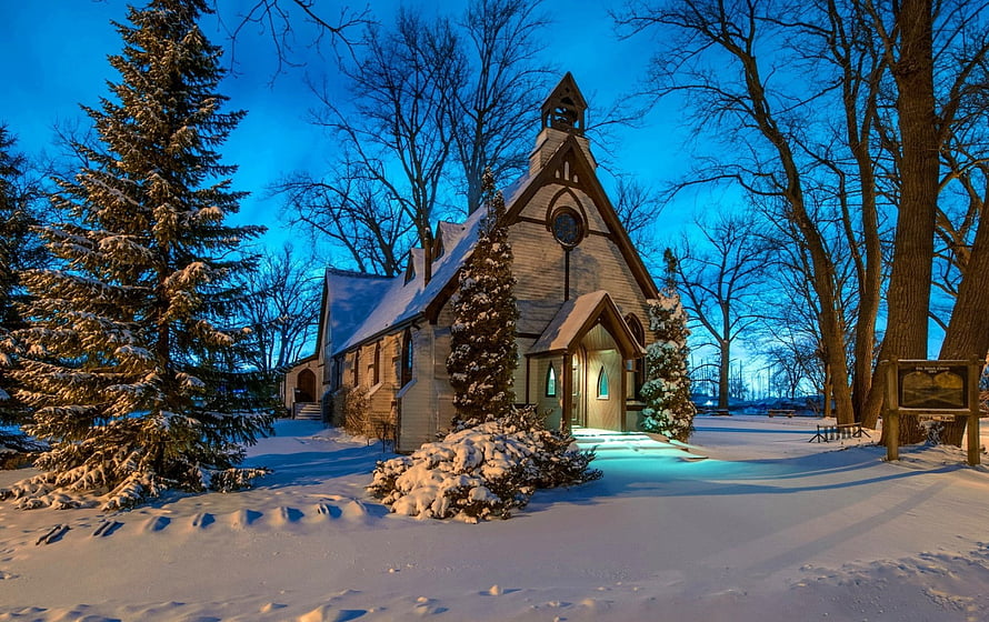 Snow-Covered Gothic Church at Blue Hour with Evergreens and Bare Trees HD wallpaper