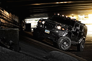 Black Hummer H2 SUV with Off-Road Tires Parked in a Dimly Lit Urban Underpass HD wallpaper