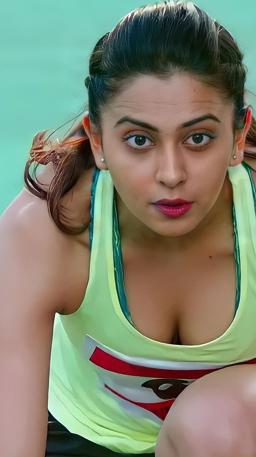 Rakul Preet Singh in a neon green athletic tank top with a teal background HD phone wallpaper