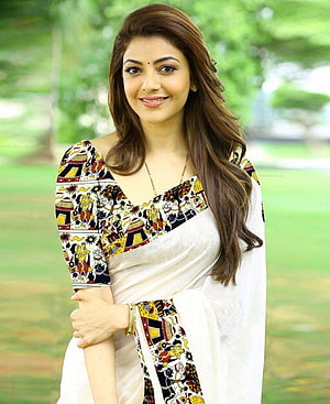 Kajal Agarwal in a white saree with colorful printed blouse standing in a green garden HD phone wallpaper