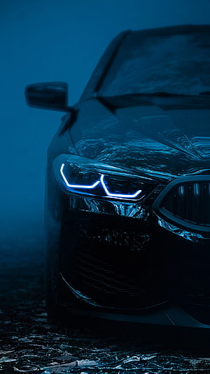 Close-up of a BMW front end with glowing blue LED headlights in a dark smoky atmosphere HD phone wallpaper