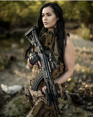 Female Soldier in Tactical Gear Holding an Assault Rifle in a Forest Setting HD phone wallpaper