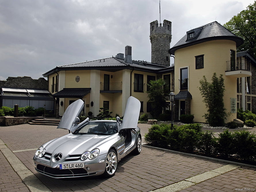 Silver Mercedes-Benz SLR McLaren with gullwing doors parked before a European castle estate HD wallpaper