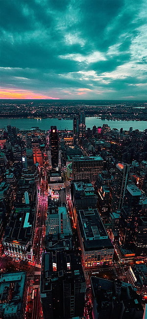 Aerial View of Manhattan Skyline at Dusk with Dramatic Teal Clouds and City Lights HD phone wallpaper