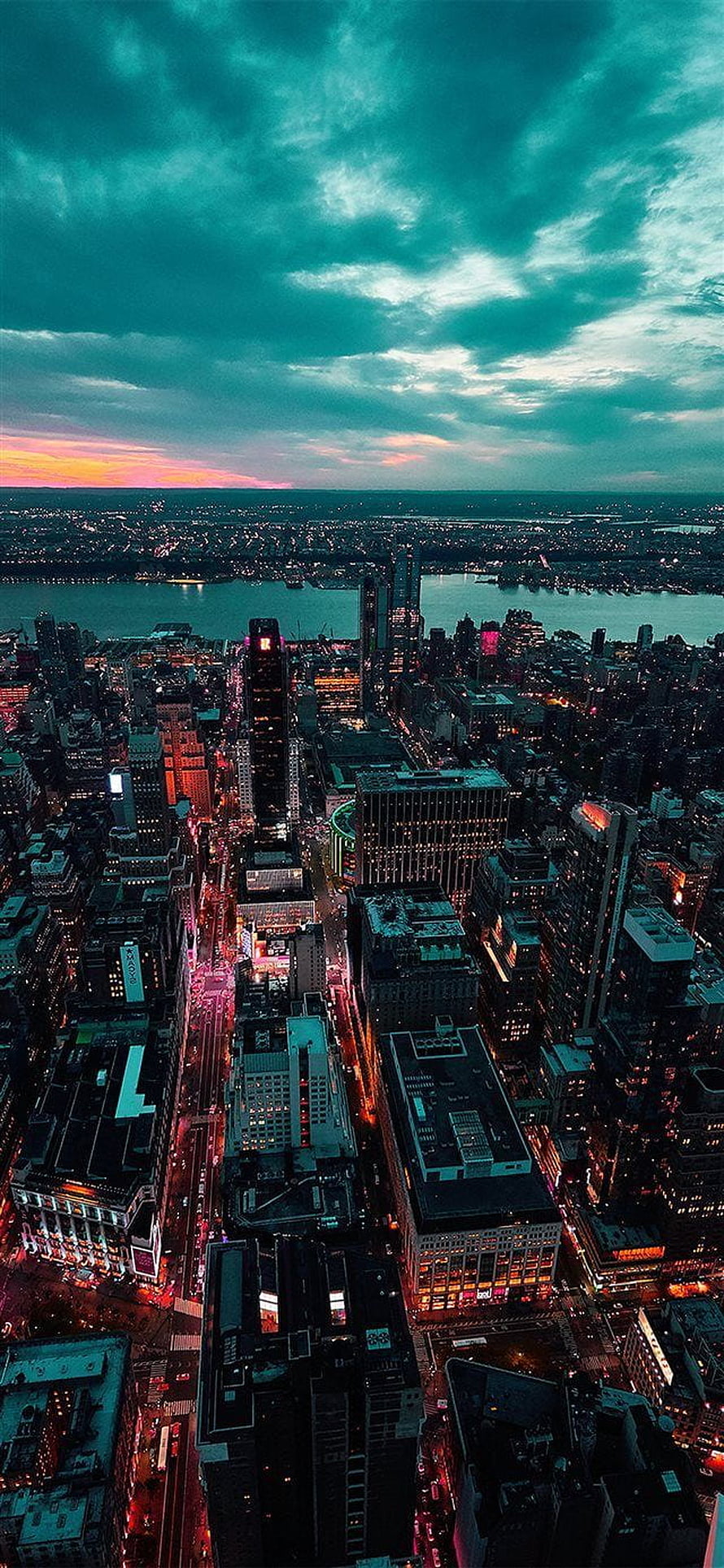 Aerial View of Manhattan Skyline at Dusk with Dramatic Teal Clouds and City Lights HD phone wallpaper