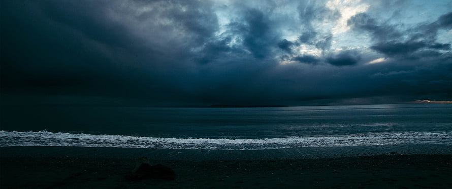Moody Ocean Horizon Under Heavy Storm Clouds at Dusk HD wallpaper