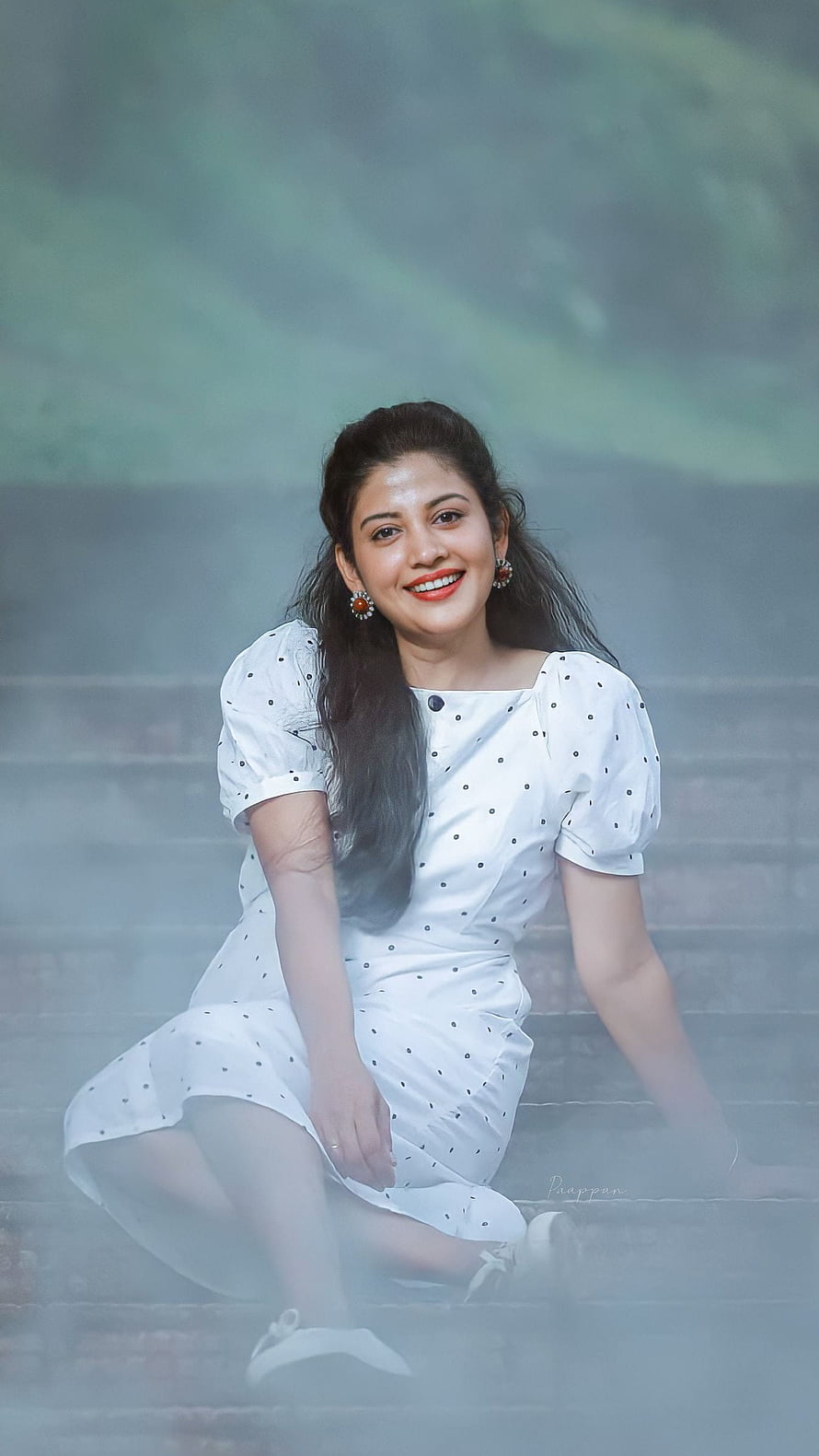 Shivada Nair in a white polka dot dress sitting on misty stone steps HD phone wallpaper