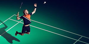 Badminton Player Leaping for a Smash on a Green Court HD wallpaper