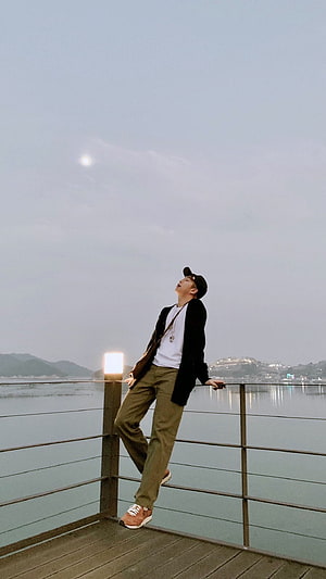 RM from BTS Leaning on a Waterfront Railing at Dusk HD phone wallpaper