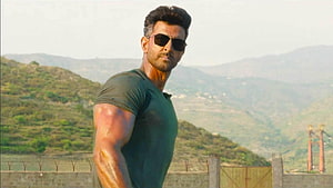 Hrithik Roshan in War movie still wearing sunglasses and green t-shirt against mountain backdrop HD wallpaper