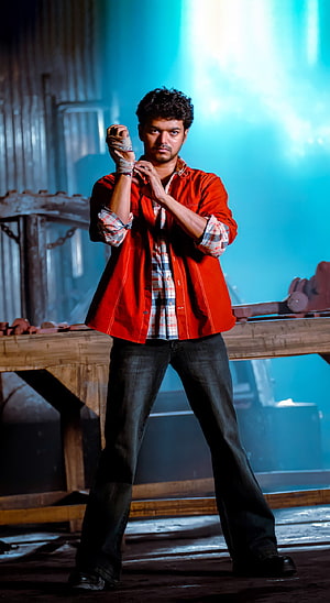 Vijay in a red jacket and plaid shirt wrapping his hands in a gritty industrial setting HD phone wallpaper