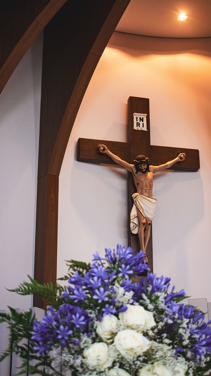 Wooden Crucifix with Jesus Christ and Floral Arrangement in Modern Church Interior HD phone wallpaper