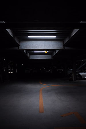 Moody Underground Parking Garage With Fluorescent Lighting And Orange Floor Markings HD phone wallpaper