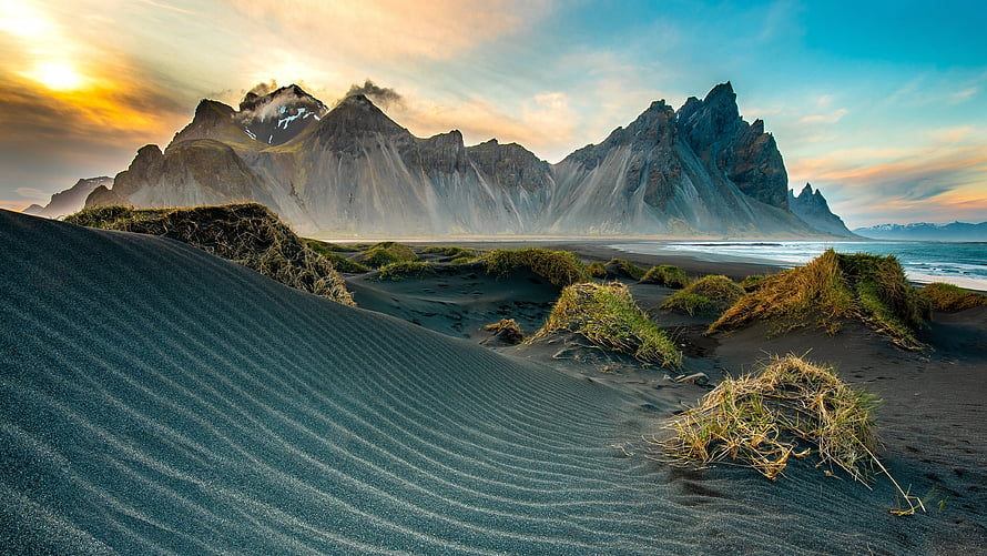 Dramatic Coastal Mountain Range Rising Above Black Sand Dunes at Golden Hour HD wallpaper