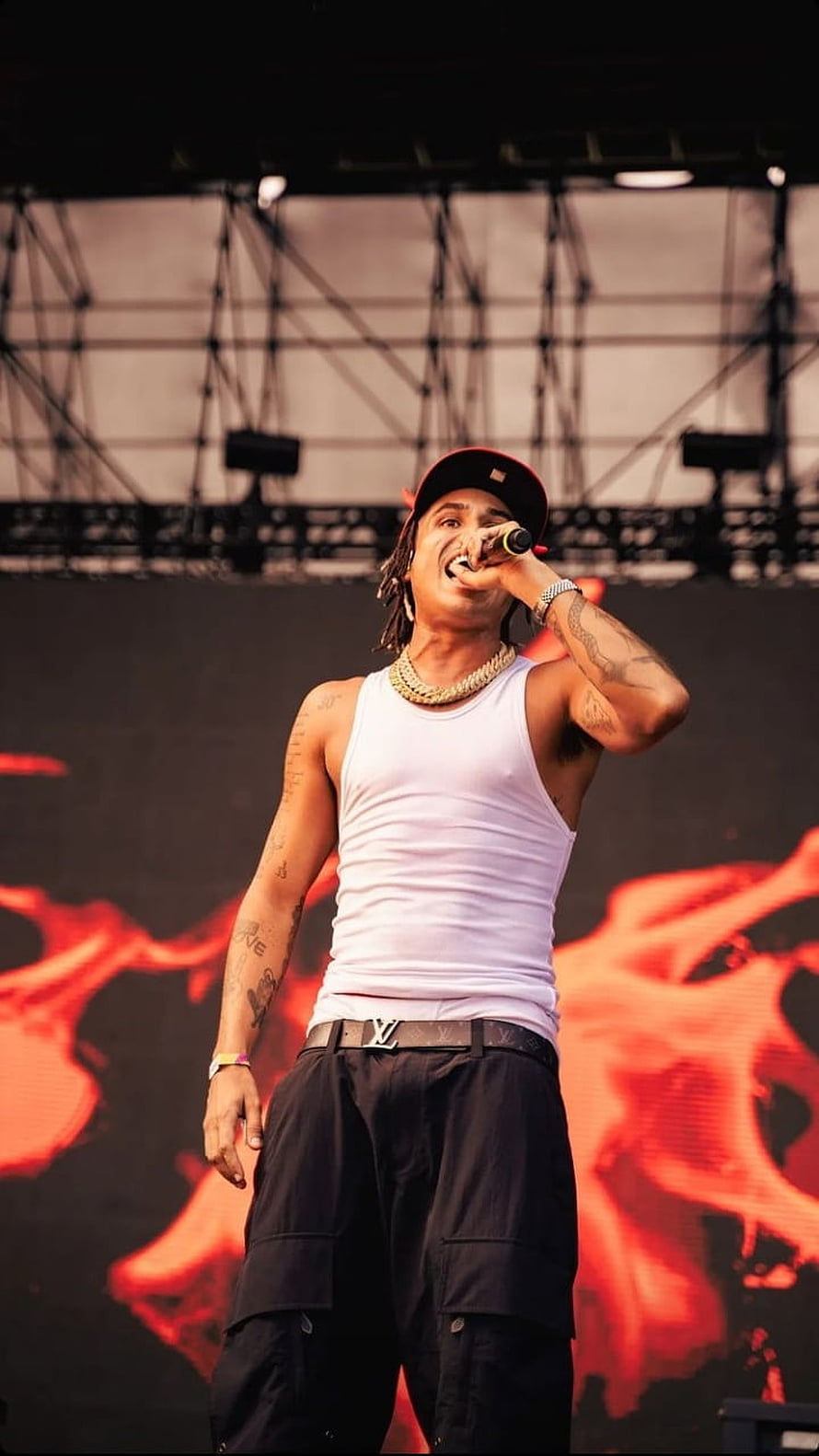 Matuê performing live on stage with microphone and red backdrop HD phone wallpaper