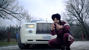 Sidhu Moose Wala Crouching in Front of White Rolls Royce Ghost in Maroon Tracksuit HD wallpaper