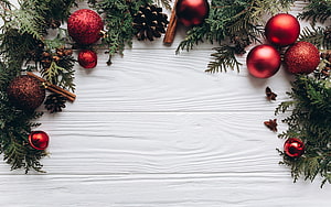 Festive Christmas border with red ornaments, pine branches, and pinecones on white wood HD wallpaper