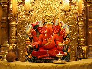 Siddhivinayak Ganesha Temple Idol with Golden Carved Backdrop and Diya HD wallpaper