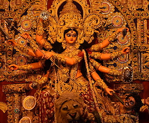 Ornate Durga Maa idol with multiple arms, lion mount, and intricate gold temple decorations HD wallpaper