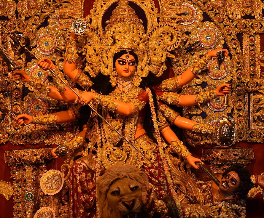 Ornate Durga Maa idol with multiple arms, lion mount, and intricate gold temple decorations HD wallpaper
