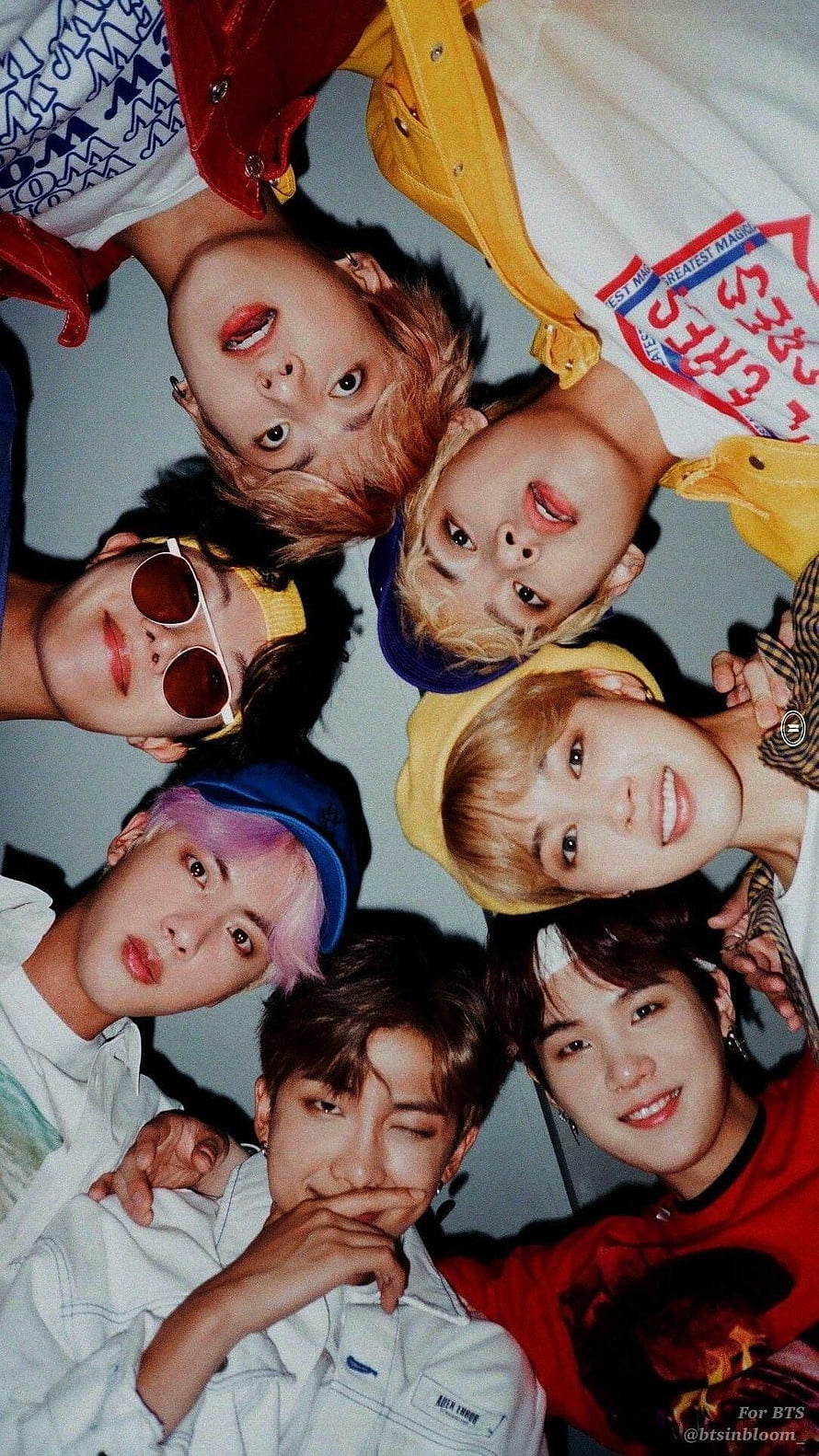 BTS Members Lying in a Circle with Colorful Hair and Playful Expressions HD phone wallpaper
