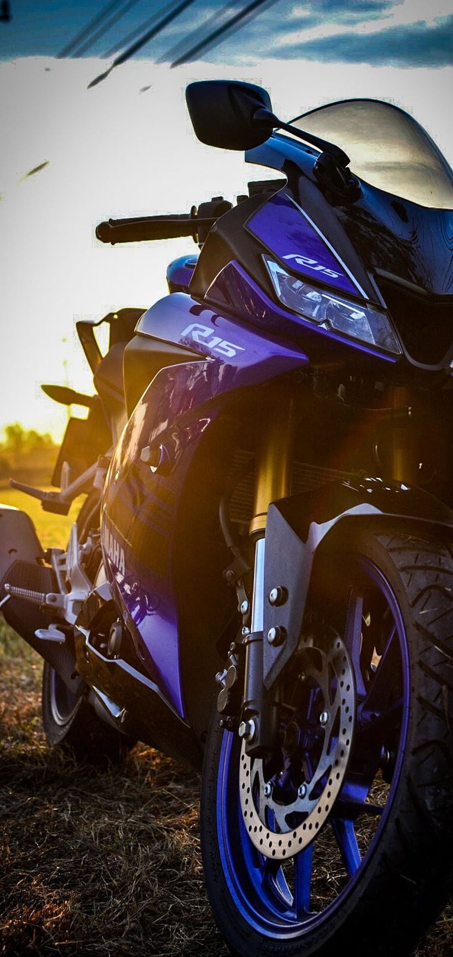 Yamaha R15 sport motorcycle parked in golden hour sunlight with dramatic sky backdrop HD phone wallpaper