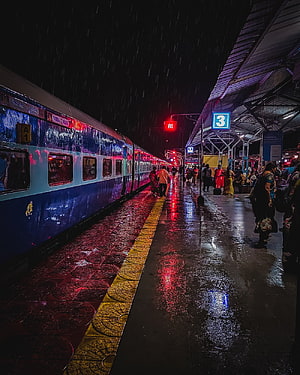 Rainy Night at Indian Railways Platform with Blue Train and Neon Reflections HD phone wallpaper