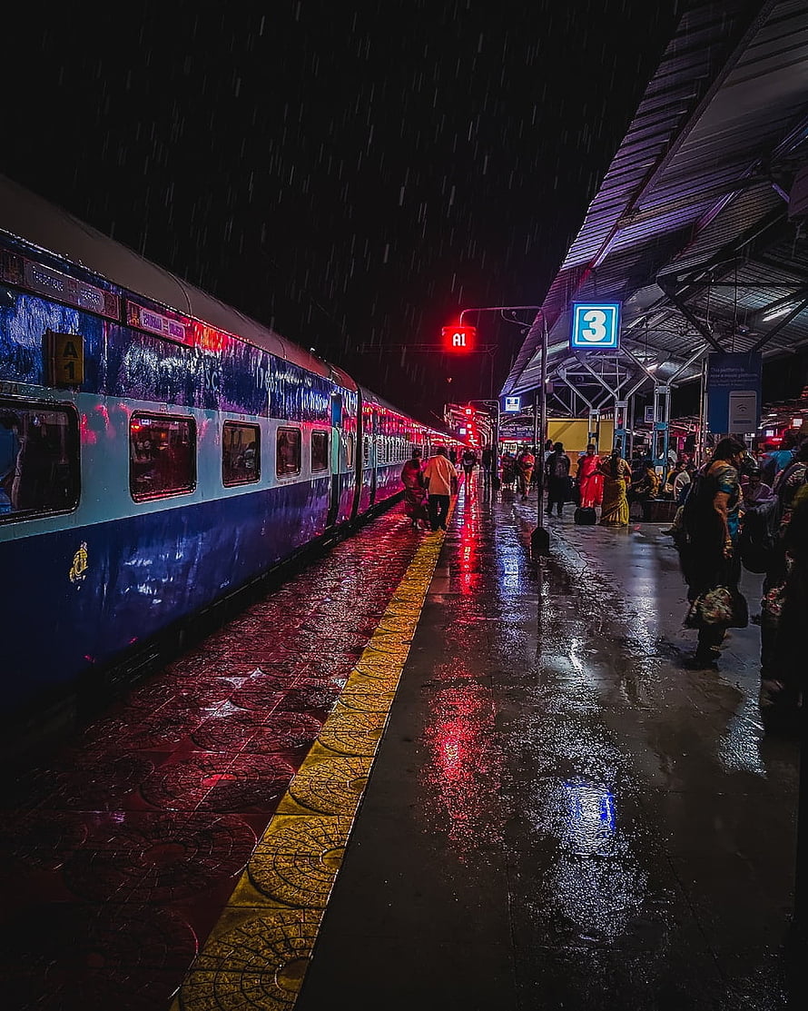 Rainy Night at Indian Railways Platform with Blue Train and Neon Reflections HD phone wallpaper