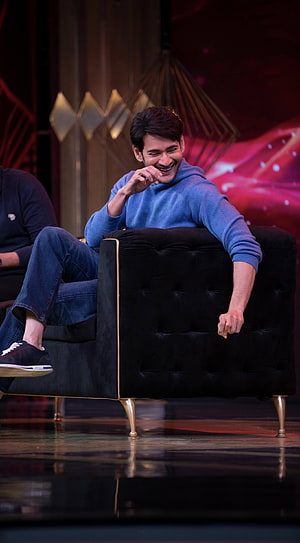 Mahesh Babu smiling in blue hoodie on a black velvet armchair at a film event HD phone wallpaper