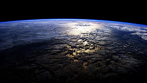 Earth From Space: Atmospheric Horizon and Sunlit Clouds Over Dark Terrain HD wallpaper