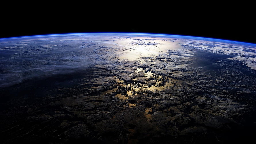 Earth From Space: Atmospheric Horizon and Sunlit Clouds Over Dark Terrain HD wallpaper