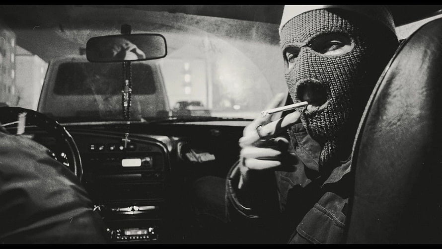 Black and white photo of a masked man smoking a cigarette inside a car HD wallpaper