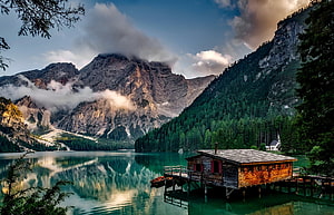 Lago di Braies in the Dolomites with rustic wooden boathouse and dramatic mountain reflections HD wallpaper