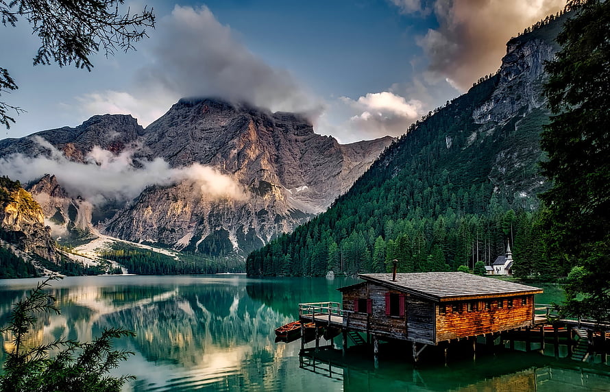 Lago di Braies in the Dolomites with rustic wooden boathouse and dramatic mountain reflections HD wallpaper