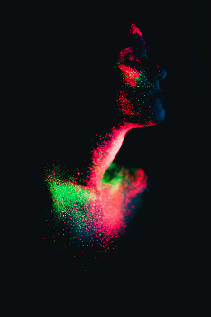 Vibrant Neon Particle Portrait of a Woman Dissolving Into Colorful Dust on Black Background HD phone wallpaper