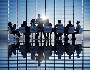 Silhouetted Business Team in Modern Conference Room with Floor Reflections HD wallpaper