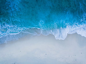 Aerial View of Turquoise Ocean Waves Rolling onto White Sandy Beach HD wallpaper