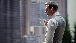 Harvey Specter holding a coffee cup on a city balcony with skyscrapers in the background HD wallpaper