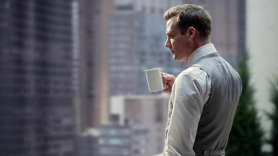 Harvey Specter holding a coffee cup on a city balcony with skyscrapers in the background HD wallpaper