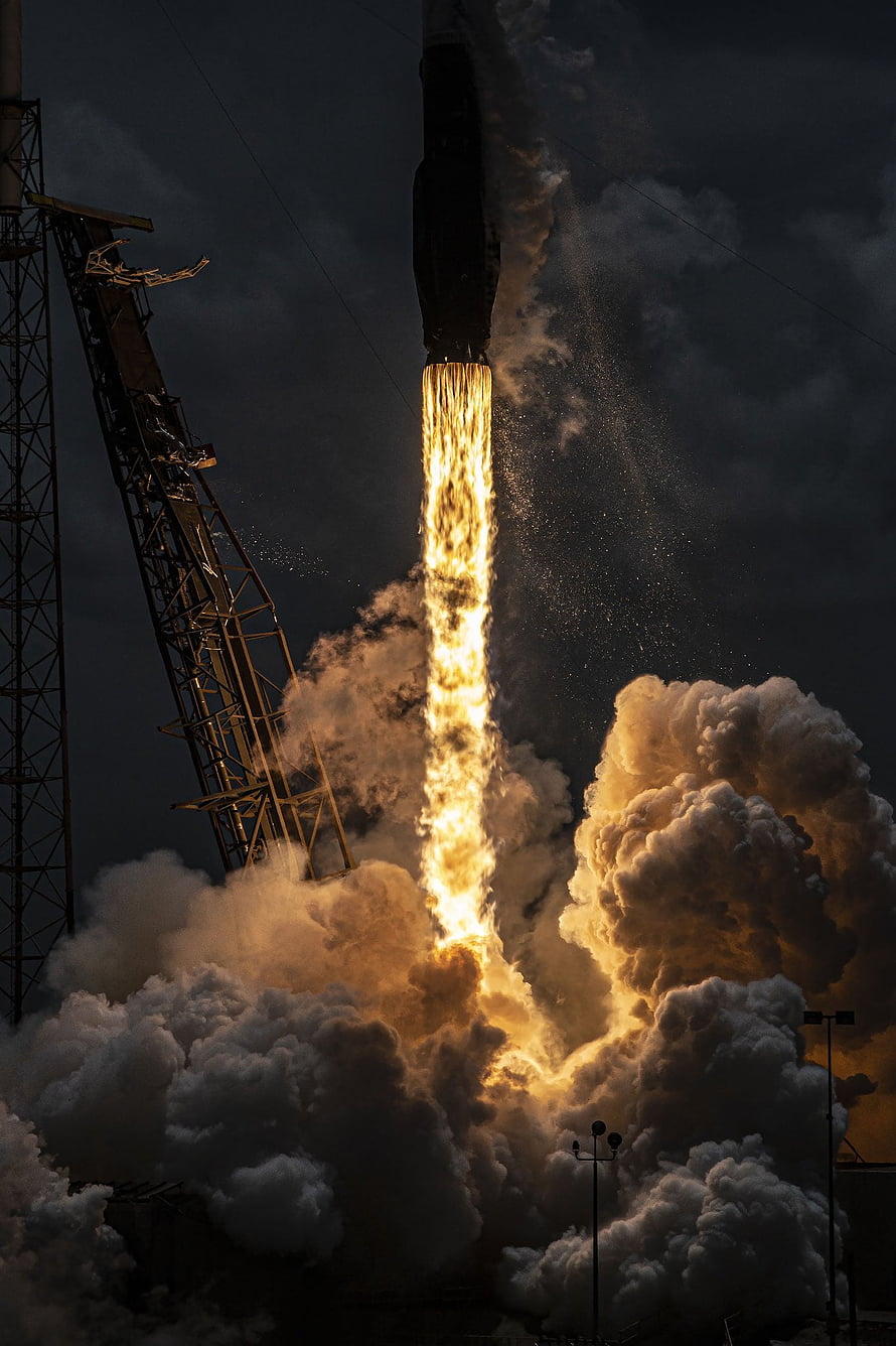 SpaceX Falcon Heavy rocket igniting engines during a dramatic nighttime launch HD phone wallpaper