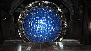 Stargate Portal in Dark Industrial Chamber with Glowing Blue Energy Core HD wallpaper