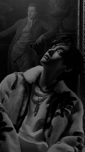 Kim Taehyung in a monochrome portrait wearing a fur coat with a classical oil painting in the background HD phone wallpaper