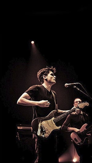 John Mayer performing live on stage with electric guitar under dramatic spotlight HD phone wallpaper