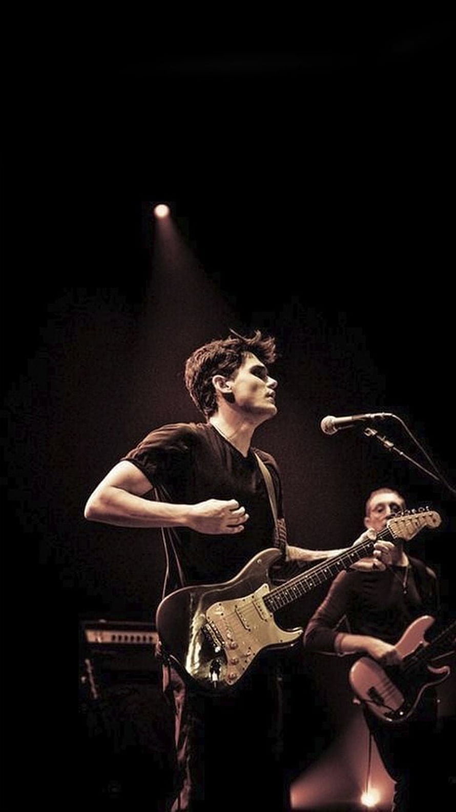 John Mayer performing live on stage with electric guitar under dramatic spotlight HD phone wallpaper
