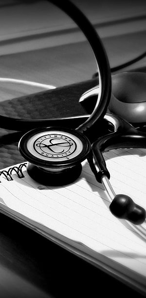 Black and White Stethoscope Resting on a Lined Notepad with Medical Equipment HD phone wallpaper