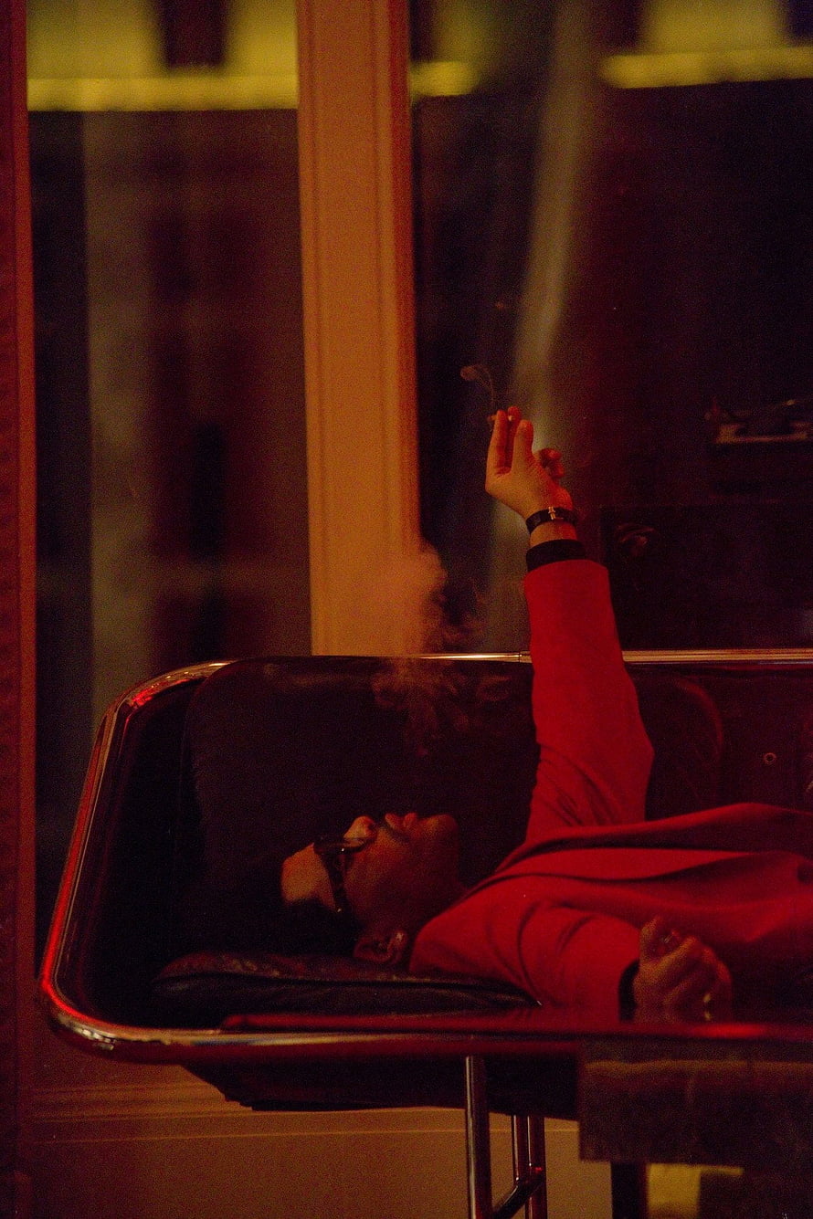 The Weeknd Reclining in Red Suit Holding Cigarette in Moody Studio HD phone wallpaper