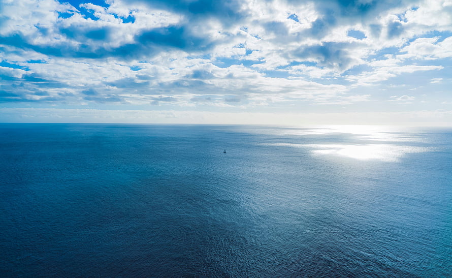 Vast Ocean Horizon Under a Bright Cloudy Sky with Sunlight Reflection HD wallpaper