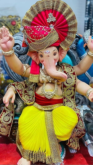 Ornate Ganesha Murti in Traditional Red and Yellow Attire with Gold Jewelry HD phone wallpaper
