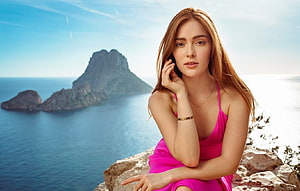 Redhead model in pink dress posing on coastal cliff with ocean and rocky island backdrop HD wallpaper